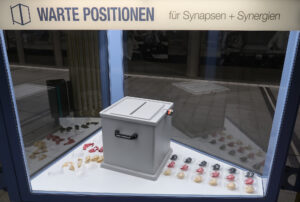 Ansicht Totale - Wahlurne mit aufgereihten schwarz rot gold Glückskeksen in Vitrine - Kunstinstallation - I would prefer not to (X) - präsentiert von Warte Positionen, U-Bahnsteig Bockenheimer Warte