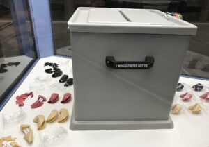 Ansicht Halbtotale - Wahlurne mit aufgereihten schwarz rot gold Glückskeksen in Vitrine - Kunstinstallation - I would prefer not to (X) - präsentiert von Warte Positionen, U-Bahnsteig Bockenheimer Warte