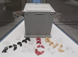 Ansicht Halbtotale - Wahlurne rückseitig mit aufgebrochenen schwarz rot gold Glückskeksen in Vitrine - Kunstinstallation - I would prefer not to (X) - präsentiert von Warte Positionen, U-Bahnsteig Bockenheimer Warte
